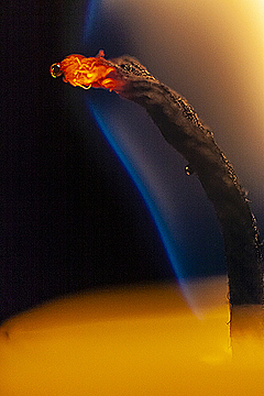 Фитиль в пламени свечи с капелькой расплавленного парафина